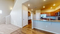 This two-story home is designed with a practical and cohesive aesthetic, combining warm tones and durable finishes throughout. The main level centers around an open-concept kitchen and living area, where rich hardwood-style flooring flows seamlessly underfoot. The kitchen is well-appointed with warm wood cabinetry extending to the upper walls, granite-style countertops, and a full suite of stainless steel appliances including a refrigerator with an in-door dispenser, an electric range, a built-in microwave, and a dishwasher. A peninsula with a raised granite countertop bar provides additional prep space and casual seating. Recessed lighting illuminates the kitchen, complementing the natural light that filters in through the windows. The adjoining living area transitions to plush carpet, creating a comfortable, defined space.

The bedrooms are carpeted and bathed in natural light through sizable windows fitted with blinds. The primary bathroom offers a dual-sink vanity with granite countertops, warm wood cabinetry, hardwood-style flooring, and a separate shower area. A secondary bathroom features a full tub-shower combo and a single vanity. A generously sized walk-in closet with multi-tiered wire shelving and hanging rods provides substantial storage capacity.