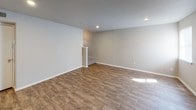 This two-story space is designed with a practical and cohesive aesthetic throughout. The main living areas feature warm wood-look flooring that extends across both levels, complemented by neutral gray walls and white baseboards that create a clean, understated backdrop. Recessed lighting illuminates the open living spaces, which are connected by a staircase with a white-railed banister visible from the upper level.

The galley-style kitchen is well-appointed with light maple cabinetry offering generous storage, dark speckled granite-look countertops, and black appliances including a range and refrigerator. Wood-look flooring continues through the kitchen, maintaining visual consistency.

Both bathrooms mirror each other in design, featuring the same light maple vanity cabinetry topped with dark granite-look countertops and single-basin sinks. One bathroom includes a shower-tub combination, while the other serves as a half bath. Both include wood-look flooring.

The bedrooms are finished with plush neutral carpet, providing warmth underfoot. One bedroom features a ceiling fan with a light fixture and a window that allows natural light to enter. A smaller carpeted room with a high window offers additional flexible space. Overall, the layout is functional and consistent in its finishes throughout.