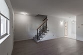 Located at 574 Turnberry Blvd in Newport News, Virginia, this two-story home offers a thoughtfully designed layout with functional living spaces across both levels. The main floor features a bright, open living area with light hardwood-style flooring that flows seamlessly throughout, complemented by natural light streaming through a front-facing window. A staircase with a wood handrail and metal balusters connects both floors and serves as a visual focal point of the main level. The kitchen is well-appointed with white shaker cabinetry, granite-look countertops, stainless steel appliances including a range, over-the-range microwave, dishwasher, and refrigerator, along with a double-basin sink and large-format tile flooring. A glass-paneled door in the kitchen provides access to the outdoors. Upstairs, the bedrooms are generously sized with soft carpeting and ample natural light. The primary bedroom features dual closets, while additional bedrooms offer walk-in closet space. A clean, bright bathroom on the upper level includes a tub-shower combination with white subway tile surround, a vanity with storage, and marble-look tile flooring. The home's neutral color palette and clean finishes create a welcoming, move-in-ready atmosphere throughout.