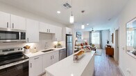 This well-appointed one-bedroom, one-bathroom residence in Surprise, AZ offers a thoughtfully designed layout that maximizes every square foot. Light-toned wood-look flooring flows throughout the main living areas, creating a cohesive and modern aesthetic.

The kitchen is a standout feature, showcasing crisp white cabinetry with matte black hardware, quartz countertops, a subway tile backsplash, and a full suite of stainless steel appliances including a refrigerator, range, microwave, and dishwasher. A central island with pendant lighting provides additional prep space and casual seating, making the kitchen as functional as it is visually appealing.

The open-concept living area is bathed in natural light from large windows dressed with sheer curtains, and is finished with a ceiling fan for year-round comfort. The space offers a relaxed, inviting ambiance well-suited for both everyday living and entertaining.

The bedroom is a comfortable retreat, featuring plush carpeting, a ceiling fan, generous natural light from a large window, and a dedicated closet for ample storage. The clean, neutral palette throughout the bedroom enhances its calm atmosphere.

Additional highlights include a private balcony and a well-designed bathroom. The overall design reflects a clean, contemporary style with quality finishes that define modern residential living.