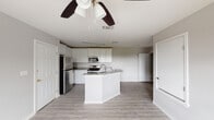 Located at 1634 14th St in Corpus Christi, TX, this single-story home offers a clean, modern aesthetic with thoughtful updates throughout. The open-concept kitchen serves as the heart of the home, showcasing crisp white shaker cabinetry extending to the ceiling, granite countertops, and a full suite of stainless steel appliances including a refrigerator, range, and built-in microwave. A central kitchen island with an integrated sink and matching granite surface provides additional workspace and adds to the open flow of the layout. Light wood-style flooring runs throughout the main living areas, complementing the neutral gray wall tones and white trim for a cohesive, contemporary feel. Ceiling fans are present in multiple rooms, enhancing comfort and air circulation. The bedrooms are well-proportioned, each featuring natural light from double-hung windows with views of the surrounding neighborhood, and are finished with the same consistent flooring and trim details. The bathroom is fitted with a full soaking tub and shower combination featuring a white tile surround and chrome fixtures, alongside dark wood-tone flooring for contrast. The overall design of the home reflects a clean, move-in-ready condition with modern finishes throughout.
