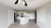 Located at 1634 14th St in Corpus Christi, TX, this single-story home offers a clean, modern aesthetic with thoughtful updates throughout. The open-concept kitchen serves as the heart of the home, showcasing crisp white shaker cabinetry extending to the ceiling, granite countertops, and a full suite of stainless steel appliances including a refrigerator, range, and built-in microwave. A central kitchen island with an integrated sink and matching granite surface provides additional workspace and adds to the open flow of the layout. Light wood-style flooring runs throughout the main living areas, complementing the neutral gray wall tones and white trim for a cohesive, contemporary feel. Ceiling fans are present in multiple rooms, enhancing comfort and air circulation. The bedrooms are well-proportioned, each featuring natural light from double-hung windows with views of the surrounding neighborhood, and are finished with the same consistent flooring and trim details. The bathroom is fitted with a full soaking tub and shower combination featuring a white tile surround and chrome fixtures, alongside dark wood-tone flooring for contrast. The overall design of the home reflects a clean, move-in-ready condition with modern finishes throughout.