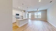 Located at 1477 Springvale Hill Drive in Kernersville, NC, this single-story, 3-bedroom, 2-bathroom home offers a well-designed open-concept layout. The combined kitchen and living area serves as the heart of the home, featuring light hardwood flooring, recessed lighting, and a ceiling fan. The kitchen is appointed with white shaker cabinetry, a classic subway tile backsplash, stainless steel appliances, and a large central island with a built-in sink and pendant lighting overhead. Natural light fills the living area through a generous window overlooking the neighborhood. The bedrooms include a spacious primary suite with hardwood flooring, a ceiling fan, and a large window, as well as additional bedrooms finished with neutral carpet. The primary bathroom offers a double-sink vanity with white cabinetry, a soaking tub, and a walk-in shower, while the second bathroom provides a single vanity and toilet in a clean, functional layout. A dedicated laundry room houses a full-size washer and dryer alongside a closet with built-in shelving. Throughout the home, neutral wall tones, clean white trim, and consistent finishes create a cohesive, move-in-ready aesthetic.