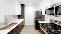 Located in the heart of Hollywood at 1446 Tamarind Ave, this single-floor unit offers a clean, modern aesthetic throughout. The open-concept living area features smooth hardwood-style flooring, bright white walls, and a sliding glass door that leads to a private balcony, filling the space with natural light. A half-wall peninsula seamlessly connects the living area to the kitchen, which is outfitted with stainless steel appliances — including a gas range, refrigerator, and microwave — complemented by dark wood cabinetry, white quartz countertops, and a herringbone tile backsplash. The bedrooms are finished with plush carpeting and feature windows that bring in additional natural light; one bedroom also includes an in-unit stacked washer and dryer. The bathrooms are designed with a contemporary sensibility, showcasing backlit vanity mirrors, undermount sinks, dark wood cabinetry with brushed nickel hardware, and white quartz countertops. One bathroom features a sliding glass shower enclosure over a soaking tub, while the other includes a separate toilet and shower area. The overall ambiance is bright, clean, and modern, with a consistent design language carried throughout every room.