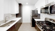 Located in the heart of Hollywood at 1446 Tamarind Ave, this single-floor unit offers a clean, modern aesthetic throughout. The open-concept living area features smooth hardwood-style flooring, bright white walls, and a sliding glass door that leads to a private balcony, filling the space with natural light. A half-wall peninsula seamlessly connects the living area to the kitchen, which is outfitted with stainless steel appliances — including a gas range, refrigerator, and microwave — complemented by dark wood cabinetry, white quartz countertops, and a herringbone tile backsplash. The bedrooms are finished with plush carpeting and feature windows that bring in additional natural light; one bedroom also includes an in-unit stacked washer and dryer. The bathrooms are designed with a contemporary sensibility, showcasing backlit vanity mirrors, undermount sinks, dark wood cabinetry with brushed nickel hardware, and white quartz countertops. One bathroom features a sliding glass shower enclosure over a soaking tub, while the other includes a separate toilet and shower area. The overall ambiance is bright, clean, and modern, with a consistent design language carried throughout every room.
