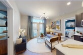 This single-floor residence showcases a contemporary open-concept design that seamlessly connects the kitchen, dining, and living areas. The kitchen is outfitted with dark wood cabinetry, quartz countertops, stainless steel appliances, and a central island with pendant lighting overhead, providing both functional workspace and casual seating. Light wood-style flooring runs throughout the main living areas, enhancing the bright, cohesive aesthetic.

The living room benefits from natural light streaming through large windows and glass doors, which open to an exterior view. A sputnik-style chandelier adds a modern accent above the seating area. Colorful artwork adorns the walls, contributing to the space's welcoming character.

The primary bedroom features large windows, plush carpeting, a ceiling fan, and a bold accent wall. It connects directly to a well-appointed bathroom complete with a walk-in glass shower finished in marble-style tile, a dark wood vanity with quartz countertop, and access to a dedicated walk-in closet. A second bedroom offers ample natural light, a ceiling fan, and generous storage. The second bathroom mirrors the unit's refined finishes, featuring a backlit mirror and quartz vanity.