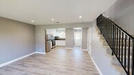 Located at 3151 Thurber Ln in Santa Cruz, California, this two-story, two-bedroom, two-bathroom home offers a well-designed layout spread evenly across two floors. Light wood-style flooring runs throughout, complemented by neutral gray walls and clean white trim, creating a cohesive, modern aesthetic.

The main level houses the kitchen and living area. The kitchen is outfitted with stainless steel appliances — including a full-size refrigerator and gas range — white shaker-style cabinetry, a under-cabinet range hood, and dark countertops that provide a stylish contrast. Recessed lighting brightens the space effectively.

Two bathrooms serve the home. One features a white vanity with a single-basin sink, stone-toned countertop, and a large mirror, while the second includes a glass-enclosed walk-in shower with white tile surround and brushed gold fixtures.

Both bedrooms are comfortably sized with neutral tones and light flooring. The primary bedroom, the larger of the two, includes multiple closet doors and access to a private outdoor balcony through a sliding glass door — offering views of the surrounding landscaping. The second bedroom features a window with garden views, bringing in natural light. A dedicated closet and hallway complete the upper level's functional layout.
