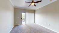 This single-floor residence offers a thoughtfully designed layout that balances comfort and functionality. The open-concept living area is anchored by plush wall-to-wall carpeting and crowned with elegant crown molding throughout. A ceiling fan with a built-in light fixture keeps the space comfortable, while a sliding glass door with vertical blinds opens to a private balcony, flooding the room with natural light and offering pleasant outdoor views of surrounding greenery.

The kitchen is a standout feature, showcasing crisp white cabinetry with brushed nickel hardware, gleaming quartz countertops, and a classic white subway tile backsplash. Stainless steel appliances, including a range, over-the-range microwave, and refrigerator, lend a modern, polished look. A peninsula with a built-in sink provides additional prep space and a natural transition into the living area.

The bedroom is generously sized with soft carpeting and a large window fitted with horizontal blinds, inviting soft, diffused natural light and views of mature trees. Crown molding and a ceiling fan complete the room's refined feel.

The bathroom features wood-look flooring, white cabinetry with ample drawer storage, quartz countertops, a framed mirror, and a tiled bathtub surround. A walk-in closet with built-in shelving and hanging rods provides excellent storage and organization.