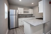 Located at 2300 Davenport Rd in Knoxville, Tennessee, this single-floor unit has been thoughtfully updated with modern finishes and a clean, neutral aesthetic throughout. Light wood-look flooring extends seamlessly across every room, complemented by crisp white trim and soft gray walls that create a bright, welcoming atmosphere.

The kitchen is a standout feature, showcasing white shaker-style cabinetry, granite countertops, a stainless steel refrigerator, a built-in cooktop, and an undermount sink. A peninsula provides additional prep space and enhances the open feel of the area. Natural light filters in through a window, adding to the kitchen's airy quality.

The living areas are generously sized, with recessed lighting overhead and wall-mounted climate control units ensuring year-round comfort. The layout flows naturally between the main living space and the private rooms, connected by a central hallway. One bedroom features a ceiling fan, a window with blinds, and its own wall A/C unit, while another includes a built-in closet with a hanging rod for convenient storage.

The bathroom is cleanly finished with a white vanity topped with granite, a round mirror, a tub-shower combination, and matching light wood flooring. The space also includes a visible electrical panel, adding a practical element to the utility areas. Overall, the unit presents a well-maintained, move-in-ready interior with consistent, modern detailing throughout.