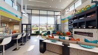This contemporary clubhouse and leasing center is defined by its striking architectural design and energetic aesthetic. The single-floor layout opens into a dramatic, double-height lobby anchored by expansive floor-to-ceiling glass walls that flood the interior with natural light and frame sweeping views of the outdoor pool and palm-tree-lined courtyard beyond.

The main lounge area is generously proportioned, featuring stylish seating arrangements adorned with vibrant teal, orange, and coral accent pillows set against neutral, taupe upholstery. A bold horizontal stripe of teal, yellow, and red wraps the upper walls, adding a lively focal point throughout the space. Statement sputnik-style chandeliers hang overhead, complementing the recessed lighting and polished tile flooring underfoot.

A built-in bookshelf with an integrated fireplace anchors the lounge's social zone, while a sleek, dark reception desk serves as the central greeting point. Decorative indoor grass planters line the glass perimeter, softening the transition between indoors and out.

A glass-enclosed business center and conference room offer a quiet, professional environment with a long dark conference table, ergonomic seating, and exterior-facing windows. A cozy media alcove with built-in bench seating, plush rugs, and colorful artwork provides an intimate retreat. Together, these spaces create a well-rounded, design-forward environment ideal for community gathering and business needs.