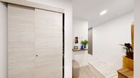 Located at 485 Perth Avenue in Toronto's vibrant Junction neighbourhood, this thoughtfully designed two-bedroom, two-bathroom unit offers a bright and contemporary living experience. Light hardwood flooring and crisp white walls flow throughout, creating a clean, cohesive aesthetic.

The open-concept living area is anchored by large floor-to-ceiling windows that flood the space with natural light and frame expansive views of green treetops and the city skyline beyond. The kitchen is seamlessly integrated into the main living zone, featuring a peninsula that provides both workspace and casual seating.

The primary bedroom is a serene retreat, benefiting from generous glazing with sliding doors that open to outdoor views of the surrounding landscape. A built-in sliding wardrobe adds practical storage. The second bedroom also enjoys large windows overlooking rooftop greenery and the neighbourhood below, offering a bright and comfortable space.

The two bathrooms are finished to a high modern standard. One features a deep soaking tub with floor-to-ceiling white tile and a built-in niche, while the second offers a glass-enclosed shower, wood-toned cabinetry, and a sleek white vanity. A welcoming hallway connects all rooms efficiently, completing this well-appointed urban residence.