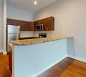 This contemporary 700 square foot apartment offers a blend of style and functionality. The open-concept living area is anchored by gleaming hardwood floors that extend throughout the space, creating a seamless flow. Large windows flood the rooms with natural light and provide urban views.

The gourmet kitchen is a standout feature, boasting rich wood cabinetry, stainless steel appliances, and elegant granite countertops. A breakfast bar with overhang adds extra seating and separates the kitchen from the living area.

The bedroom, measuring 140 square feet, offers ample space and features a large window for natural light. Two well-appointed bathrooms provide convenience and luxury, with one showcasing a spacious vanity and glass-enclosed shower.

Modern amenities include recessed lighting, climate control, and in-unit laundry facilities. The thoughtful layout maximizes the use of space, with a hallway connecting the various rooms. Located at 777 S Broad, unit 305, this apartment combines urban sophistication with comfortable living in a prime location.