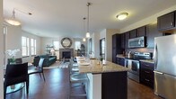 Located at 1300 S Barker Rd in Brookfield, Wisconsin, this thoughtfully designed single-floor residence offers a seamless blend of modern finishes and functional living. The open-concept layout connects the kitchen, dining, and living areas into one cohesive space, making it ideal for both everyday living and entertaining.

The kitchen is a standout feature, showcasing dark espresso cabinetry, stainless steel appliances, a decorative tile backsplash, and a generously sized granite-topped island with pendant lighting and bar seating. A convenient in-unit washer and dryer are tucked nearby. The living room centers around a tile-surround fireplace flanked by windows that bring in abundant natural light, creating a warm and inviting atmosphere. Rich hardwood-style flooring flows throughout the main living areas.

The dining area is positioned adjacent to floor-to-ceiling sliding glass doors that open to a private balcony, offering picturesque outdoor views — a perfect spot for relaxing or dining al fresco. The bedroom is carpeted for comfort and features a large window with natural views, ample closet space with sliding barn-style doors, and a calm, restful ambiance. The bathroom is finished with dark cabinetry, a stone-topped vanity, and tile flooring, maintaining the cohesive, contemporary aesthetic found throughout the home.