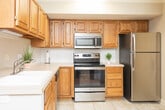 Located at 210 Raven Ridge Dr in Kernersville, NC, this two-story home offers a thoughtfully arranged layout across both levels, connected by a staircase visible in the floor plan. The main level features a living room with warm hardwood flooring, crown molding, a ceiling fan, and a window that allows natural light to fill the space. Adjacent to the living area, the dining room continues the hardwood flooring and opens to the outdoors through a sliding glass door, enhancing the connection between interior and exterior spaces.

The kitchen is well-appointed with abundant oak cabinetry, white countertops, a classic subway tile backsplash, and a full suite of stainless steel appliances including a range, microwave, dishwasher, and refrigerator. Light tile flooring completes the practical yet inviting kitchen design. A dedicated laundry room provides added convenience, housing a full-size washer and dryer beneath upper oak cabinetry.

The bedrooms are carpeted and comfortable, each receiving natural light through windows with blinds. The bathroom features tile flooring, an oak vanity, and a tub-shower combination. Crown molding and textured ceilings are consistent throughout, lending a cohesive and polished character to the home.
