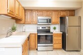 Located at 210 Raven Ridge Dr in Kernersville, NC, this two-story home offers a thoughtfully arranged layout across both levels, connected by a staircase visible in the floor plan. The main level features a living room with warm hardwood flooring, crown molding, a ceiling fan, and a window that allows natural light to fill the space. Adjacent to the living area, the dining room continues the hardwood flooring and opens to the outdoors through a sliding glass door, enhancing the connection between interior and exterior spaces.

The kitchen is well-appointed with abundant oak cabinetry, white countertops, a classic subway tile backsplash, and a full suite of stainless steel appliances including a range, microwave, dishwasher, and refrigerator. Light tile flooring completes the practical yet inviting kitchen design. A dedicated laundry room provides added convenience, housing a full-size washer and dryer beneath upper oak cabinetry.

The bedrooms are carpeted and comfortable, each receiving natural light through windows with blinds. The bathroom features tile flooring, an oak vanity, and a tub-shower combination. Crown molding and textured ceilings are consistent throughout, lending a cohesive and polished character to the home.