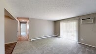 Located at 7440 Fair Ct in Florence, Kentucky, this single-floor unit offers a practical and straightforward layout designed for comfortable everyday living. The living area is generously proportioned, featuring neutral-toned carpet, a textured ceiling, and a large sliding glass door fitted with vertical blinds that allows natural light to filter in while providing views of the surrounding greenery. Baseboard heating runs along the walls, ensuring efficient warmth throughout the space.

A hallway connects the living area to the rest of the unit, leading to multiple carpeted bedrooms. Each bedroom includes a window with blinds, baseboard heating, and a wall-mounted air conditioning unit, providing year-round climate control. One bedroom also features a closet door, adding practical storage.

The galley-style kitchen is efficiently arranged, offering ample white cabinetry extending to the ceiling, light marble-style countertops, a stainless steel sink, and white appliances including a range and refrigerator. Wood-look plank flooring runs through the kitchen and into the bathroom.

The bathroom is clean and functional, featuring a white vanity with under-sink storage, a medicine cabinet with mirror, and a separate tub and shower area accessed through an interior door. The overall ambiance of the space is neutral, bright, and move-in ready.
