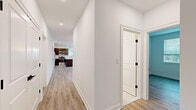 Located at 15 High St in Norwell, MA, this well-appointed 3-bedroom, 2-bathroom home offers a thoughtfully designed single-floor layout. Light-toned luxury vinyl plank flooring runs throughout, lending a cohesive, modern aesthetic to every room.

A central hallway connects the living spaces, leading toward a contemporary kitchen equipped with dark cabinetry, stainless steel appliances including a range and microwave, and pendant lighting that adds a stylish focal point. The living room is bright and open, benefiting from multiple windows that invite natural light and offer views of the surrounding greenery.

The three bedrooms are well-proportioned and finished with the same clean, neutral palette found throughout the home. The spacious primary bedroom features dual windows, recessed lighting, and generous room to accommodate a full furniture arrangement. Additional bedrooms also include windows with views of the outdoors, providing a comfortable and airy feel.

Storage is well addressed, with two closets featuring wire shelving systems for organized storage. The two bathrooms are finished in a crisp, modern style — one includes a glass-enclosed walk-in shower with white subway tile, a wood-toned vanity with ample cabinetry, and light tile flooring. The home also includes a staircase, suggesting access to additional levels or utility space. Overall, the space presents a fresh, move-in-ready environment with clean finishes throughout.