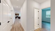 Located at 15 High St in Norwell, MA, this well-appointed 3-bedroom, 2-bathroom home offers a thoughtfully designed single-floor layout. Light-toned luxury vinyl plank flooring runs throughout, lending a cohesive, modern aesthetic to every room.

A central hallway connects the living spaces, leading toward a contemporary kitchen equipped with dark cabinetry, stainless steel appliances including a range and microwave, and pendant lighting that adds a stylish focal point. The living room is bright and open, benefiting from multiple windows that invite natural light and offer views of the surrounding greenery.

The three bedrooms are well-proportioned and finished with the same clean, neutral palette found throughout the home. The spacious primary bedroom features dual windows, recessed lighting, and generous room to accommodate a full furniture arrangement. Additional bedrooms also include windows with views of the outdoors, providing a comfortable and airy feel.

Storage is well addressed, with two closets featuring wire shelving systems for organized storage. The two bathrooms are finished in a crisp, modern style — one includes a glass-enclosed walk-in shower with white subway tile, a wood-toned vanity with ample cabinetry, and light tile flooring. The home also includes a staircase, suggesting access to additional levels or utility space. Overall, the space presents a fresh, move-in-ready environment with clean finishes throughout.
