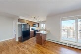 Located at 4623 199 Street NW in Edmonton, Alberta, this well-appointed 2-bedroom, 2-bathroom unit offers a comfortable and functional single-floor layout. Warm hardwood-style flooring flows consistently throughout, lending a cohesive and inviting feel to every room.

The open living area is generously sized, filled with natural light from multiple windows, and features a classic flush-mount light fixture that adds a clean, understated touch. Adjacent to the living space, the galley-style kitchen is thoughtfully designed with rich dark wood cabinetry, granite-look countertops, a double undermount sink, and black stainless appliances including a gas range with over-the-range microwave and a full-size refrigerator. A window above the counter brings in additional natural light.

The primary bedroom offers a comfortable footprint with a dedicated closet featuring built-in shelving. The second bedroom is equally bright, with a window overlooking the surrounding neighbourhood. Both bathrooms are clean and functional — one features a full soaker tub and surround, while the other includes hardwood-style flooring, a vanity with granite countertop, and modern fixtures.

A dedicated in-unit laundry room houses a full-size washer and dryer, adding everyday convenience. Neutral tones and baseboard heating throughout complete this practical and well-maintained home.
