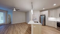 This single-floor residence offers a thoughtfully designed open-concept layout that seamlessly connects the kitchen and living areas. The kitchen serves as a central hub, featuring a large island with an undermount sink and granite countertops, light-toned cabinetry with modern hardware, and a full suite of stainless steel appliances including a refrigerator, range, microwave, and dishwasher. A dedicated laundry closet is conveniently accessible from the kitchen. Pendant lighting and recessed fixtures illuminate the space, while light wood-style flooring extends throughout the main living areas, adding warmth and continuity.

The living area is open and airy, highlighted by a ceiling fan and track lighting. The bedrooms are carpeted for comfort and each include ceiling fans and ample closet access. Windows dressed with blinds allow natural light to filter in. The primary bathroom features a walk-in glass-enclosed shower, a granite-topped vanity with light wood cabinetry, and wood-style flooring. A second full bathroom offers a tub-shower combination, matching vanity finishes, and the same cohesive flooring. Neutral tones and clean finishes throughout create a contemporary, move-in-ready atmosphere.