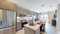Located at 50 N McQueen Rd in Gilbert, AZ, this thoughtfully designed one-bedroom, two-bathroom residence offers a well-appointed single-floor layout. The open-concept kitchen and living area serve as the heart of the home, featuring gray shaker-style cabinetry, quartz countertops, a spacious island with bar seating, and a full suite of stainless steel appliances including a gas range, microwave, and French door refrigerator. Light wood-tone flooring flows throughout the main living areas, enhancing the bright, airy atmosphere. The living room is accented by a bold slate-blue feature wall and large sliding glass doors that open to a private balcony, flooding the space with natural light and offering open views of the surrounding Gilbert neighborhood. The bedroom is a calm retreat with plush carpet, a ceiling fan, large windows, and a matching slate-blue accent wall. It connects to a walk-in closet with built-in shelving and rod systems for organized storage. Both bathrooms are finished with gray vanity cabinetry, white quartz counters, and wood-look flooring. The primary bath includes an LED-lit mirror and in-unit washer and dryer. Recessed lighting throughout ties together the modern, cohesive design of this efficient and stylish residence.