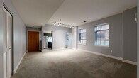 Located at 1 Canal Square Plaza in the heart of downtown Akron, Ohio, this single-floor unit offers a well-designed layout with a cohesive, contemporary aesthetic throughout. The open-concept living area is immediately welcoming, featuring neutral-toned carpet, cool gray walls with crisp white trim, and a sleek track lighting system that provides flexible, directional illumination. Multiple windows fitted with horizontal blinds allow natural light to filter in while offering views of the surrounding urban brick exteriors.

The galley-style kitchen is efficiently arranged with dark espresso cabinetry, white countertops, wood-look flooring, and stainless steel appliances including a refrigerator and range, making the most of the available space.

The bedrooms continue the unit's consistent gray color palette, with plush carpeting and windows that bring in natural light. One bedroom features a darker, more intimate finish, while others are bright and airy with ample wall space.

The bathroom is finished in a clean, modern style with wood-toned floating vanity cabinetry, a white countertop with integrated sink, and wood-look vinyl flooring. The overall ambiance of the space is understated and functional, with a urban-residential character well-suited to the vibrant Canal Square Plaza location.