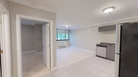 Located at 360 Main St in Hartford, CT, this efficient one-bedroom, one-bathroom unit offers a well-designed layout across a single floor. The open living area features neutral gray-toned walls, large white tile flooring, crown molding, and a window that brings in natural light with views of surrounding greenery. A wall-mounted HVAC unit provides individual climate control.

The kitchen is a standout feature, offering a modern L-shaped design with high-gloss gray cabinetry, dark granite countertops, a white tile backsplash, and a full suite of stainless steel appliances including a refrigerator, range, microwave, and dishwasher. Crown molding carries through from the living area, adding a refined touch.

The bedroom is a quiet, comfortably sized space with light-toned flooring, a large window with blinds, and a wall-mounted HVAC unit. Two closets provide ample storage throughout the unit.

The bathroom is tastefully updated with large-format beige floor tiles, wainscoting-style wall tile, a wall-mounted floating vanity with a rectangular sink, a framed mirror with contemporary sconce lighting, and a glass-enclosed shower. The overall aesthetic throughout the unit is clean, modern, and functional, making it a practical living space in downtown Hartford.