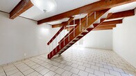 This two-story, 2-bedroom, 1-bathroom home in Columbus, Ohio offers a thoughtfully laid-out floor plan spread evenly across two levels. The main floor features an open-concept living and dining area defined by striking exposed wood beam ceilings and light stone tile flooring, creating a warm, rustic character. A bold wood-and-white staircase serves as an architectural focal point, connecting both levels. The kitchen is well-equipped with white cabinetry, granite-style countertops, black appliances including a refrigerator, gas range, and microwave, all set on matching tile flooring. A patio provides convenient outdoor access from the main level. Upstairs, the two bedrooms feature light wood-tone laminate flooring, neutral gray walls, and windows that bring in natural light. The spacious primary bedroom includes a ceiling fan and an arched window, adding a classic touch. The upper level also includes a hallway, four closets, a full bathroom, and a dedicated laundry area, offering practical storage and functionality. A utility room rounds out the home's amenities. With its distinctive exposed beam aesthetic, updated finishes, and efficient two-level layout, this home offers a comfortable and characterful living experience in Columbus.