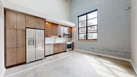 Located at 2400 Grayland Ave in Richmond, VA, this two-story loft masterfully blends industrial character with modern finishes. The main floor immediately impresses with soaring ceilings, polished concrete floors, and a dramatic painted brick accent wall. A large steel-framed window floods the open living and kitchen area with natural light and urban views. The kitchen is well-equipped with warm wood cabinetry, white subway tile backsplash, stainless steel appliances including a side-by-side refrigerator, electric range, microwave, and dishwasher, all set against a clean quartz countertop. Exposed HVAC ductwork throughout adds to the loft's industrial aesthetic. The upper floor houses the spacious primary bedroom, featuring a ceiling fan, a skylight for abundant natural light, and two generous closets offering ample storage. Two full bathrooms are finished with consistent modern detailing — white subway tile, sleek floating vanities with brushed nickel hardware, and large-format floor tile. One bathroom features a tub-shower combination, while the other offers a walk-in glass shower. Connecting the two floors are staircases that reinforce the home's open, multi-level character, making this Richmond loft a distinctive and functional urban retreat.