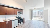 Located at 3120 Heritage Trail Blvd in Denton, TX, this modern one-bedroom, two-bathroom unit offers a thoughtfully designed open-concept layout across a single floor. Light wood-tone flooring flows consistently throughout the space, complementing the clean white walls and creating a bright, cohesive aesthetic.

The kitchen is a standout feature, equipped with rich dark wood cabinetry, a white tile backsplash, stainless steel appliances including a refrigerator, electric range, built-in microwave, and dishwasher, and a track lighting system overhead. It opens directly into the living area, which benefits from abundant natural light and access to a private balcony through sliding glass doors, offering views of the surrounding urban landscape. A ceiling fan adds comfort to the living space.

The bedroom is a well-proportioned, sunlit room featuring a large window with horizontal blinds that frame outdoor views. A hallway connects the bedroom to closet space and the bathrooms, maintaining a practical and organized flow. One bathroom includes a full tub-shower combination, a wood-trimmed vanity with a white countertop, and a large mirror.

The unit's modern finishes, natural light, and functional layout make it a well-appointed urban residence in Denton.