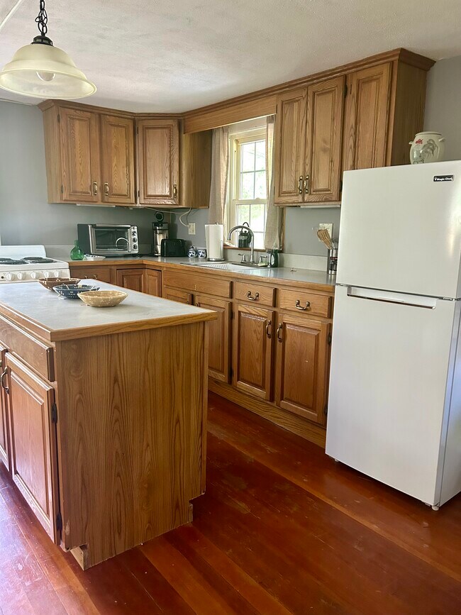 Espacio de encimera en isla de cocina, gabinetes de madera y refrigerador. - 32 Meadow St