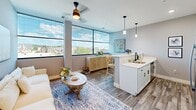 Located in Manchester, NH, this 2-bedroom, 2-bathroom residence offers a well-designed, single-floor layout that maximizes every square foot of its compact footprint. The open-concept living and kitchen area is the heart of the home, featuring wide-plank wood-look flooring, a ceiling fan, and an expansive bank of large windows that flood the space with natural light and frame views of the surrounding cityscape. The kitchen is outfitted with white cabinetry, quartz countertops, a peninsula with bar seating, pendant lighting, and stainless steel appliances, flowing seamlessly into the living area for an effortless, functional design.

The primary bedroom offers a comfortable, cozy retreat with plush carpeting and neutral walls, while the second bedroom mirrors the same calm aesthetic, featuring a horizontal transom window. Both rooms are finished with crisp white panel doors and matte black hardware, consistent throughout the unit. The two bathrooms are clean and functional, with one featuring a tub-shower combo equipped with matte black fixtures and wood-look flooring. A stacked in-unit washer and dryer adds everyday convenience. The overall palette of soft grays, whites, and warm wood tones creates a cohesive, modern, and inviting atmosphere throughout.