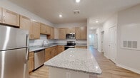 Located at 4420 Taylor Rd in Nashville, TN, this single-floor, 3-bedroom, 2-bathroom home offers a well-designed layout with modern finishes throughout. The open-concept living, dining, and kitchen area serves as the heart of the home, featuring light hardwood-style flooring, recessed lighting, and a seamless flow between spaces. The kitchen is well-appointed with light maple cabinetry, granite countertops, a large center island, and a full suite of stainless steel appliances including a refrigerator, dishwasher, range, and microwave. A hallway connects the bedrooms, each fitted with ceiling fans and natural light from windows with blinds. The spacious primary bedroom offers a generous footprint and easy access to a bathroom featuring matching maple cabinetry, granite countertops, a tall linen tower, and a large mirror. Four closets provide ample storage throughout. A dedicated laundry area and utility room add practicality, while a private balcony overlooks a lush, tree-lined backdrop. The clean, neutral color palette and consistent finishes lend the home a cohesive, modern feel throughout.