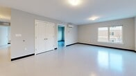 Located at 908 Hartford Tpke in Waterford, Connecticut, this single-floor unit offers a clean, modern layout designed for comfortable living. The space features durable, light-toned vinyl flooring and neutral-painted walls throughout, creating a bright and cohesive aesthetic.

The kitchen serves as a central hub, anchored by a peninsula island with a dark laminate countertop, double stainless steel sink, and seating space beneath stylish pendant lighting. White cabinetry lines the perimeter walls, complemented by a full suite of white appliances including a refrigerator, stove, and microwave. Ample storage is provided by upper and lower cabinets along the kitchen wall.

The main living area is generously proportioned, bathed in natural light from windows overlooking the exterior. A wall-mounted mini-split HVAC unit ensures year-round climate control. The bedroom features a walk-in closet outfitted with wire shelving and hanging rods, providing practical organization space.

The full bathroom is appointed with white cabinetry, a dark countertop vanity, a wall-mounted mirror, grab bars, and a tub-shower combination. An additional half bathroom offers a toilet and countertop space. Dark baseboards throughout the unit provide a crisp contrast to the light floors and walls, lending a polished, well-defined finish to every room.