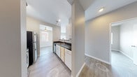 This single-floor unit offers a clean, modern aesthetic with a practical and functional layout. The galley-style kitchen is thoughtfully designed with white cabinetry accented by warm wood trim, dark countertops, and stainless steel appliances including a refrigerator and electric range. A double sink and dishwasher add to the kitchen's utility, and light wood-look luxury vinyl plank flooring runs throughout the main areas, providing a cohesive and easy-to-maintain finish.

The living area is generously proportioned, bathed in natural light through a large sliding glass door fitted with vertical blinds and a side window, creating a bright and airy atmosphere. An additional room with LVP flooring and wide windows overlooking the surrounding neighborhood provides flexible living or dining space.

The unit includes two bedrooms — one with plush carpeting and another with LVP flooring — each featuring windows with blinds that invite natural light while maintaining privacy. The bathroom is well-equipped with a vanity featuring matching white cabinetry and dark countertops, a large mirror, overhead lighting, and wood-look flooring. Neutral gray tones on the walls complement the light flooring throughout, contributing to a clean and contemporary ambiance across the entire unit.