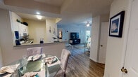 This single-story residence offers a thoughtfully designed open-concept layout that connects its primary living spaces seamlessly. The kitchen serves as a functional hub, featuring white cabinetry, a tray ceiling with track lighting, a built-in range, and a peninsula with bar seating that opens directly to the dining area. Adjacent to the kitchen, the dining space accommodates a glass-top table and flows naturally into the living room, where wood-look flooring continues throughout and a ceiling fan provides comfort overhead. The living room is bright and welcoming, with large windows fitted with blinds and patterned curtains allowing ample natural light.

Two bedrooms are carpeted and each equipped with ceiling fans and windows that bring in natural light. The primary bedroom is generously proportioned, while the secondary bedroom features its own distinct character. Both rooms provide comfortable retreats. Two full bathrooms serve the residence; each includes a tub-shower combination, a single-sink vanity with white cabinetry, and a large mirror. Wood-look flooring extends into both bathrooms, maintaining a cohesive aesthetic. The overall design is consistent and practical throughout.