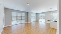 Located along Berkley Pkwy in Kansas City, MO, this single-floor unit presents a modern, well-appointed interior with a clean, contemporary design. The open-concept living and dining area is a standout feature, characterized by light hardwood-style flooring, neutral gray walls, and an impressive arrangement of large windows and glass sliding doors fitted with horizontal blinds. These expansive windows flood the space with natural light and offer views of the surrounding greenery.

The kitchen integrates seamlessly with the main living area, featuring white cabinetry, a stainless steel refrigerator, and a peninsula with pendant lighting above, providing both functionality and visual continuity. The open layout allows for effortless flow between the kitchen, dining, and living zones.

The bedrooms are carpeted for comfort, each equipped with a ceiling fan and generous window coverage that invites natural light. The bathrooms are finished to a high standard, with dual-sink vanities featuring dark stone countertops, white cabinetry, framed mirrors, and chrome fixtures. One bathroom includes a glass-enclosed walk-in shower, while another offers a combined tub and shower. Hardwood-style flooring carries through the bathroom spaces, reinforcing the cohesive, modern aesthetic found throughout the unit.