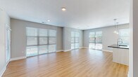 Located along Berkley Pkwy in Kansas City, MO, this single-floor unit presents a modern, well-appointed interior with a clean, contemporary design. The open-concept living and dining area is a standout feature, characterized by light hardwood-style flooring, neutral gray walls, and an impressive arrangement of large windows and glass sliding doors fitted with horizontal blinds. These expansive windows flood the space with natural light and offer views of the surrounding greenery.

The kitchen integrates seamlessly with the main living area, featuring white cabinetry, a stainless steel refrigerator, and a peninsula with pendant lighting above, providing both functionality and visual continuity. The open layout allows for effortless flow between the kitchen, dining, and living zones.

The bedrooms are carpeted for comfort, each equipped with a ceiling fan and generous window coverage that invites natural light. The bathrooms are finished to a high standard, with dual-sink vanities featuring dark stone countertops, white cabinetry, framed mirrors, and chrome fixtures. One bathroom includes a glass-enclosed walk-in shower, while another offers a combined tub and shower. Hardwood-style flooring carries through the bathroom spaces, reinforcing the cohesive, modern aesthetic found throughout the unit.