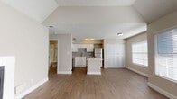 This well-appointed single-floor residence offers an open and airy layout designed for comfortable everyday living. The living area is a standout, featuring soaring vaulted ceilings with a ceiling fan, a white-surround fireplace as a focal point, and large windows dressed with blinds that allow abundant natural light to fill the space. Wood-look flooring flows seamlessly throughout, lending warmth and continuity to the interior.

The kitchen is thoughtfully designed with white shaker-style cabinetry, a gray subway tile backsplash, and gleaming white countertops, including a central island that provides additional prep space and casual seating. A full suite of stainless steel appliances — including a refrigerator, range, microwave, and dishwasher — rounds out this functional and stylish kitchen.

Adjacent to the living area, the bedroom benefits from its own generous closet with bi-fold doors and multiple windows that invite natural light. The bathroom is clean and classic, featuring a white vanity with under-cabinet storage, a large mirror with bright overhead lighting, and a tub/shower combination. A textured ceiling adds subtle architectural detail throughout the home, contributing to its overall cozy yet modern character.