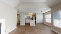This well-appointed single-floor residence offers an open and airy layout designed for comfortable everyday living. The living area is a standout, featuring soaring vaulted ceilings with a ceiling fan, a white-surround fireplace as a focal point, and large windows dressed with blinds that allow abundant natural light to fill the space. Wood-look flooring flows seamlessly throughout, lending warmth and continuity to the interior.

The kitchen is thoughtfully designed with white shaker-style cabinetry, a gray subway tile backsplash, and gleaming white countertops, including a central island that provides additional prep space and casual seating. A full suite of stainless steel appliances — including a refrigerator, range, microwave, and dishwasher — rounds out this functional and stylish kitchen.

Adjacent to the living area, the bedroom benefits from its own generous closet with bi-fold doors and multiple windows that invite natural light. The bathroom is clean and classic, featuring a white vanity with under-cabinet storage, a large mirror with bright overhead lighting, and a tub/shower combination. A textured ceiling adds subtle architectural detail throughout the home, contributing to its overall cozy yet modern character.
