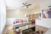 Located at 945 S Mesa Hills Dr in El Paso, Texas, this single-floor residence offers a thoughtfully designed open-concept layout with modern finishes throughout. The kitchen is a standout feature, boasting dramatically high vaulted ceilings, dark espresso cabinetry, light stone countertops, and stainless steel appliances. A central island with pendant lighting serves as a natural gathering point, complemented by bold red bar stools. Wood-look flooring flows seamlessly through the main living areas, connecting the kitchen to the bright, airy living room, which features large windows with vertical blinds that invite abundant natural light and a ceiling fan overhead. Multiple bedrooms provide comfortable retreats, each with plush carpet, ceiling fans, and windows with curtains. One bedroom showcases a striking exposed brick accent wall, while another features a bold geometric plaid wallpapered accent wall, adding distinct character to each space. Two full bathrooms are finished with dark espresso vanities, white countertops, and tub-shower combinations with tile surrounds. The overall ambiance of the home is modern and vibrant, with an eclectic mix of colorful artwork and decor lending warmth and personality to every room.