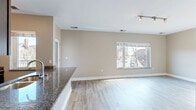This efficiently designed 1-bedroom, 1-bathroom unit offers a thoughtful open-concept layout that maximizes every square foot of living space. The interior is unified by light hardwood-style flooring that flows seamlessly from room to room, complemented by neutral warm-toned walls and clean white trim throughout.

The kitchen serves as a functional centerpiece, outfitted with rich dark espresso cabinetry, granite countertops, and a full suite of stainless steel appliances including a refrigerator with ice dispenser, range, and microwave. A peninsula with a granite breakfast bar and undermount sink opens directly to the living area, creating an ideal space for entertaining or casual dining.

The living area is generously proportioned, bathed in natural light from a large picture window that frames views of the surrounding neighborhood. Track lighting overhead provides additional illumination. The bedroom offers a comfortable footprint with its own window, dedicated closet, and direct access to adjacent spaces.

The bathroom is finished with large-format tile flooring, a dark vanity with granite countertop, an undermount sink, and a well-lit mirror framed by modern vanity lighting. A tiled shower completes the space. The unit also includes a dedicated closet for added storage convenience.