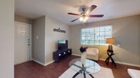This single-floor residence offers a cohesive and practical layout designed for comfortable everyday living. Rich, dark wood-style flooring flows consistently throughout the space, providing a warm and unified aesthetic across all rooms.

The living area serves as the heart of the home, featuring a ceiling fan with integrated lighting, a textured ceiling, and a large window with horizontal blinds that allows ample natural light. Neutral gray walls create a versatile backdrop, complemented by a glass-top coffee table and a plush area rug.

Adjacent to the living area, the dining space accommodates a round glass dining table beneath a pendant light fixture, with a pass-through opening connecting directly to the kitchen. The kitchen is well-equipped with light wood cabinetry, a black range, over-the-range microwave, refrigerator, and a double sink with ample counter space.

The bedroom is a calm and restful retreat, featuring its own ceiling fan, a wide window for natural light, and enough space for a full bedroom suite including a dresser and nightstands.

The bathroom includes a single-sink vanity with light countertops, a large mirror, under-sink cabinetry, and direct access to the bedroom, offering a convenient and private layout.