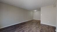 Located at 5900 Kinkead Ave in Fort Smith, Arkansas, this single-floor unit offers a practical and well-appointed layout throughout. The living areas feature rich, dark hardwood-style flooring that extends through the main spaces, complemented by neutral gray walls and textured ceilings that lend a clean, cohesive aesthetic. Natural light filters in through window blinds, brightening the generously sized living and dining areas.

The galley-style kitchen is efficiently designed with white cabinetry, granite-patterned countertops, a stainless steel sink, and black appliances including a full-size refrigerator. The layout maximizes counter and storage space along both sides of the kitchen corridor.

The bedrooms are finished with plush carpeting and each include ceiling fans with lighting. One bedroom features a distinctive painted brick accent wall, adding character to the space, while others offer closets with built-in shelving for organized storage. Windows in the bedrooms allow for natural light and ventilation.

The bathroom is appointed with a full soaking tub and shower surround in white, consistent dark wood-style flooring, and a vanity with a granite-patterned countertop. Chrome fixtures and accessories throughout provide a polished finishing touch. The overall layout, visible in the dollhouse view, reflects a compact yet functional floor plan suited for everyday living.