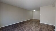 Located at 5900 Kinkead Ave in Fort Smith, Arkansas, this single-floor unit offers a practical and well-appointed layout throughout. The living areas feature rich, dark hardwood-style flooring that extends through the main spaces, complemented by neutral gray walls and textured ceilings that lend a clean, cohesive aesthetic. Natural light filters in through window blinds, brightening the generously sized living and dining areas.

The galley-style kitchen is efficiently designed with white cabinetry, granite-patterned countertops, a stainless steel sink, and black appliances including a full-size refrigerator. The layout maximizes counter and storage space along both sides of the kitchen corridor.

The bedrooms are finished with plush carpeting and each include ceiling fans with lighting. One bedroom features a distinctive painted brick accent wall, adding character to the space, while others offer closets with built-in shelving for organized storage. Windows in the bedrooms allow for natural light and ventilation.

The bathroom is appointed with a full soaking tub and shower surround in white, consistent dark wood-style flooring, and a vanity with a granite-patterned countertop. Chrome fixtures and accessories throughout provide a polished finishing touch. The overall layout, visible in the dollhouse view, reflects a compact yet functional floor plan suited for everyday living.