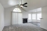 Located at 6350 Eubank Blvd NE in Albuquerque, NM, this single-story residence offers a well-designed layout with a variety of notable interior features throughout. The expansive living room immediately impresses with soaring vaulted ceilings, a ceiling fan with light fixture, and a striking arched window that floods the space with natural light. A tile-surround fireplace serves as a central focal point, while plush carpeting and vertical blinds add comfort and privacy. The living area extends into a bright bay-windowed nook, ideal as a sitting or dining area. The galley-style kitchen is thoughtfully appointed with white cabinetry, gray countertops, a white subway tile backsplash, wood-look luxury vinyl flooring, and a full suite of stainless steel appliances including a refrigerator, range, microwave, and dishwasher. The bedroom is generously sized with soft carpet, a ceiling fan, and access to a spacious walk-in closet. The bathroom features wood-look flooring, a wide vanity with gray countertop, white cabinetry, and a full tub-shower combo. A dedicated in-unit laundry area accommodates a full-size washer and dryer. The overall aesthetic is clean, neutral, and move-in ready.