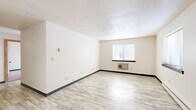 This single-floor, 2-bedroom, 2-bathroom unit offers a functional and thoughtfully arranged layout. The living area is bright and open, featuring light-toned vinyl plank flooring and a window that allows natural light to fill the space, complete with a wall-mounted HVAC unit for year-round comfort. The galley-style kitchen is a standout feature, showcasing rich cherry wood cabinetry, granite countertops with subtle grey veining, a decorative tin tile backsplash, track lighting, a stainless steel sink, and black appliances including a gas range and refrigerator. Both bedrooms are carpeted and well-proportioned, with the primary bedroom offering a comfortable footprint and windows that bring in natural light. The second bedroom is equally bright, with a large window overlooking the surrounding neighborhood. A central hallway, framed by warm wood-trimmed doors, connects the rooms and includes access to a dedicated closet for additional storage. The two bathrooms are clean and functional; one features a tiled tub-shower combination with classic light blue square tiles and chrome fixtures. The overall design is clean and neutral, creating a versatile canvas throughout.