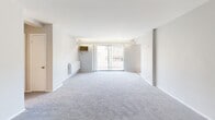 Located at 1217 Delaware Ave, this single-floor, 2-bedroom, 1-bathroom unit offers 740 square feet of functional living space. The layout includes two bedrooms, a kitchen, a full bathroom, and a connecting hallway. The expansive primary bedroom measures 390 square feet and features plush gray carpeting, soft neutral wall tones, and a large closet with sliding doors. A second bedroom also features gray carpet and neutral walls, providing a versatile space suitable for a guest room or home office. The kitchen is equipped with warm wood cabinetry, dark granite-style countertops, and black appliances including a refrigerator, dishwasher, and range, complemented by a stainless microwave and track lighting overhead. Light wood-look vinyl flooring runs throughout the kitchen, adding a clean, modern touch. The bathroom features wood-look vinyl flooring, a tiled shower-tub combo, and a white vanity. The main living area is generously sized, featuring gray carpet and a sliding glass door that allows an abundance of natural light to fill the space. Throughout the unit, neutral tones and clean lines create a bright, move-in-ready atmosphere.