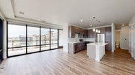 Located at 4811 S Niagara St in Denver, CO, this contemporary single-floor residence offers a thoughtfully designed open-concept layout filled with abundant natural light. The living and dining area is anchored by dramatic floor-to-ceiling windows and sliding glass doors that frame striking views of the Denver skyline, flooding the space with daylight and creating a seamless connection to the outdoors.

The kitchen is a standout feature, showcasing rich dark cabinetry, a marble-inspired tile backsplash, crisp white quartz countertops, and a center island with pendant lighting overhead. Stainless steel appliances — including a refrigerator, range, microwave, and dishwasher — complete the space. Light wood-tone flooring runs throughout the main living areas, adding warmth and continuity.

The bedroom offers plush carpeting, a ceiling fan, and a window with views of the surrounding area. A spacious walk-in closet provides generous built-in shelving and hanging rods for ample storage. The bathroom features a tub-shower combo enclosed in floor-to-ceiling tile with a clean, neutral palette. The overall ambiance is modern and polished, with finishes that reflect a high standard of contemporary urban living in the heart of the Denver metro area.