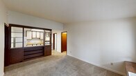 Located at 5555 McIntosh Ct in Dayton, Ohio, this single-floor, one-bedroom, one-bathroom unit offers a practical and functional layout. The living area features neutral-toned carpet, white walls, and a front entry door flanked by a window that allows natural light to fill the space. A distinctive dark wood room divider with open shelving separates the living area from the kitchen, creating a semi-open pass-through design. The kitchen is equipped with light wood-tone countertops, white cabinetry, a gas range, a full-size refrigerator, and tile flooring, providing ample workspace for everyday cooking. The bedroom is a comfortable size, with carpeted floors, a ceiling fan with light fixture, crown molding, and a window with blinds that offers an outdoor view. Warm wood-toned bi-fold closet doors provide generous storage. The bathroom includes a full tub-shower combination with chrome fixtures and a clean, functional design. A dedicated utility room adds practical value. Throughout the unit, warm brown door and trim accents provide a consistent design thread, giving the space a cohesive, classic character well-suited for comfortable everyday living.